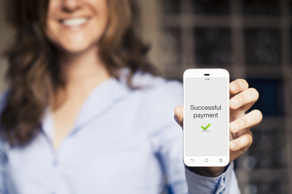 Woman holding up her phone that says Successful Payment on the screen.